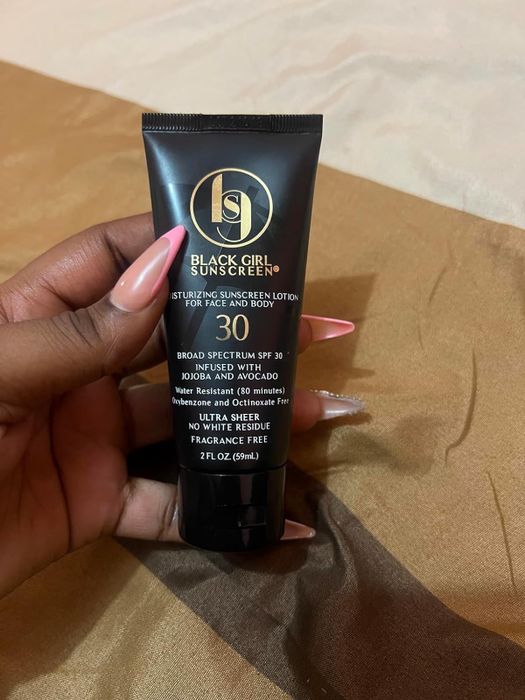 A hand holding a bottle of Black Girl Sunscreen SPF 30