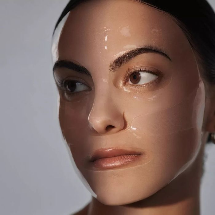 A close-up of a model wearing a shiny, transparent face mask