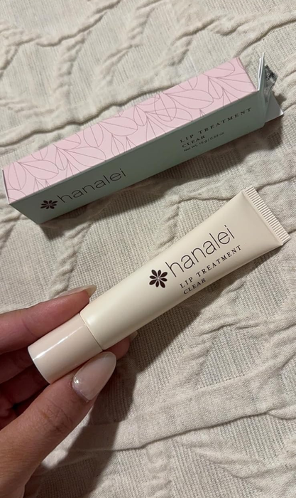 A reviewer holding the Hanalei Lip Treatment Cream with its box in the background. The article is listed under Shopping