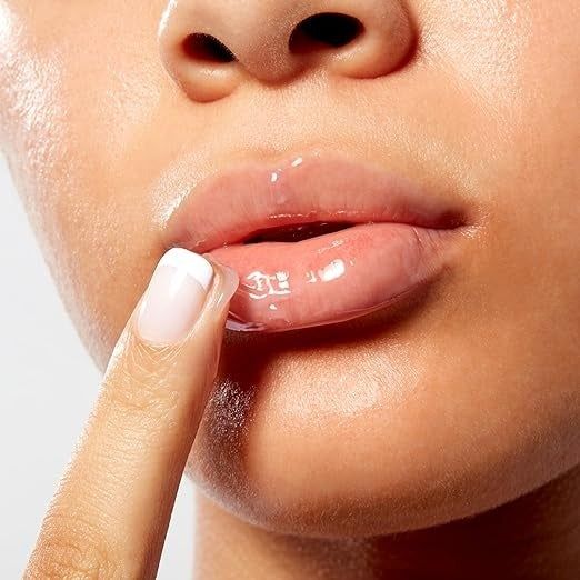 Close-up shot of someone applying a clear lip gloss with their finger.