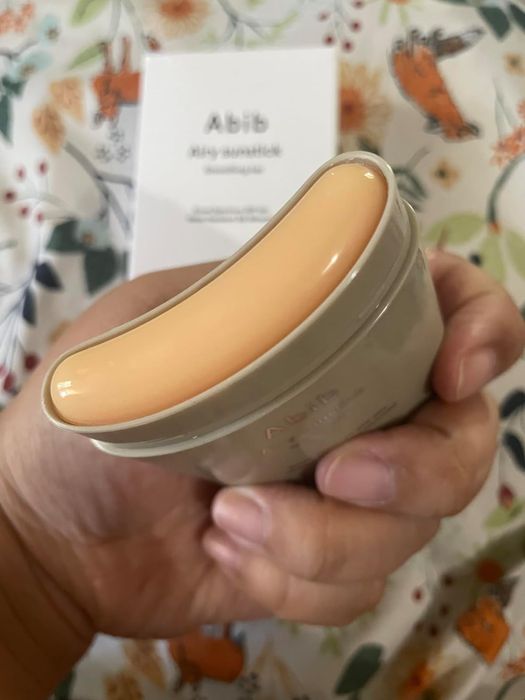 A person holding an Abib sunscreen stick, demonstrating its smooth and creamy texture