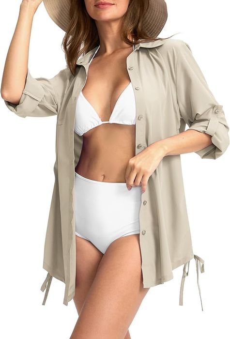 A model wearing a light-colored, button-down SPF cover-up shirt paired with a sun hat