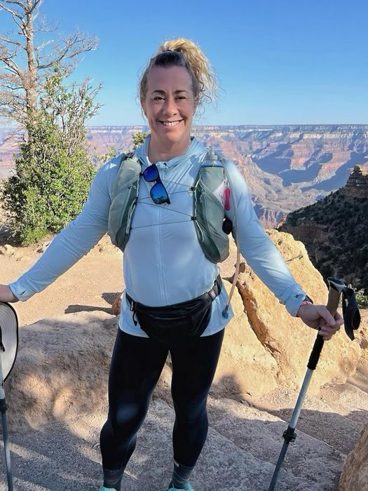 A reviewer standing on a rocky trail, wearing a light blue sun-protective jacket