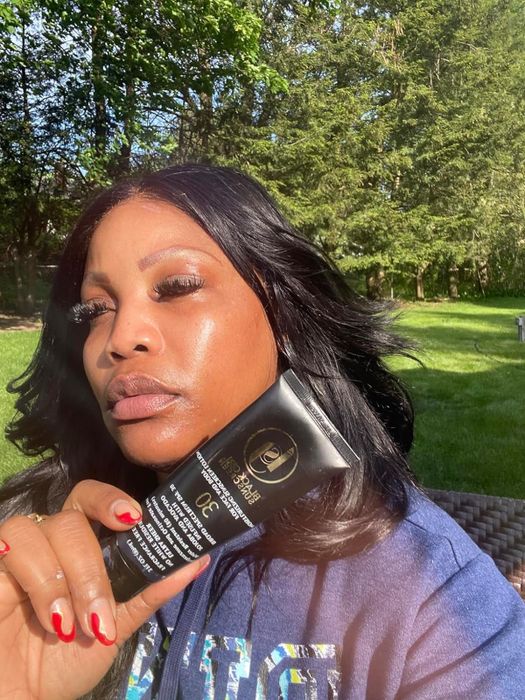 A reviewer holding up a black tube of Black Girl Sunscreen
