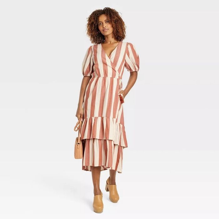 A model wearing the vertical striped dress featuring a tiered skirt