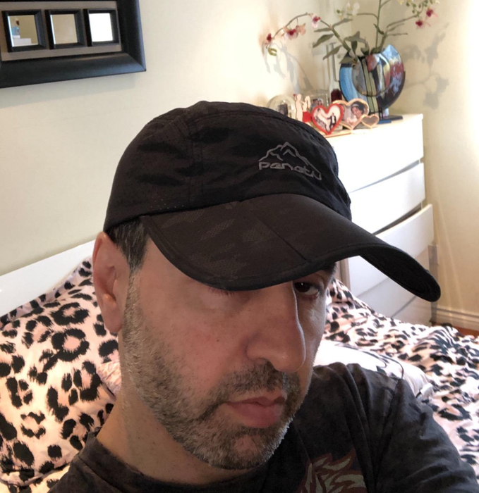A reviewer wearing a black sun-protective cap