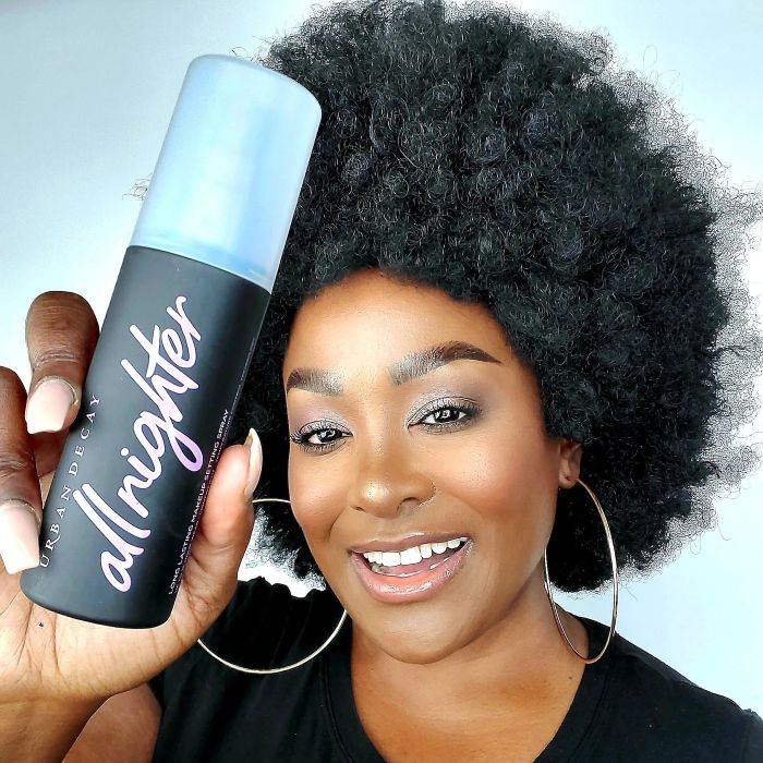 A model holding a black and purple jar of the spray