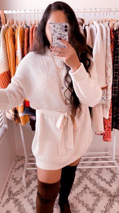 Reviewer modeling a cream-colored waffle-knit tie dress paired with black knee-high boots