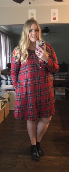 Reviewer modeling a red long-sleeve plaid mini dress with a hand in the pocket