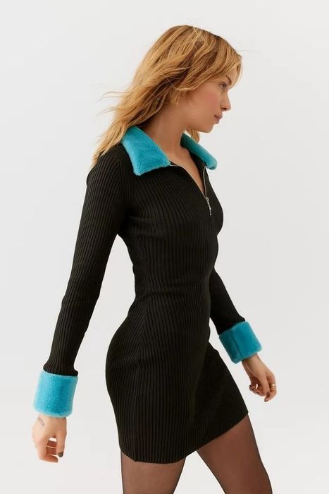 Model wearing a black long-sleeve dress with blue faux-fur trim on the sleeves and collar