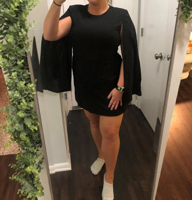 Reviewer modeling a black cape-sleeve mini dress