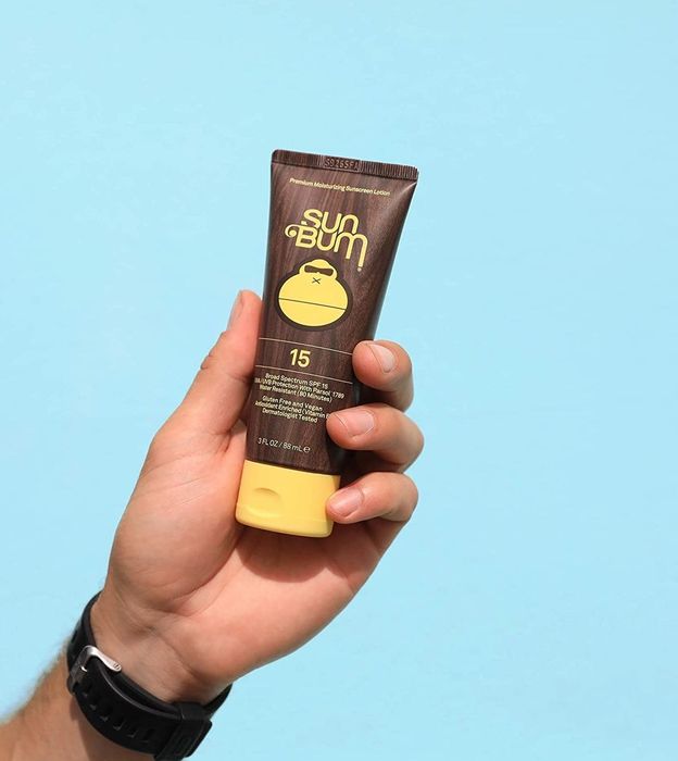 a model holding a tube of Sun Bum sunscreen