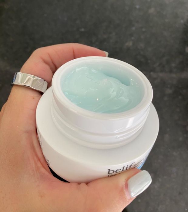 a reviewer displaying the open jar, revealing the light blue cream inside