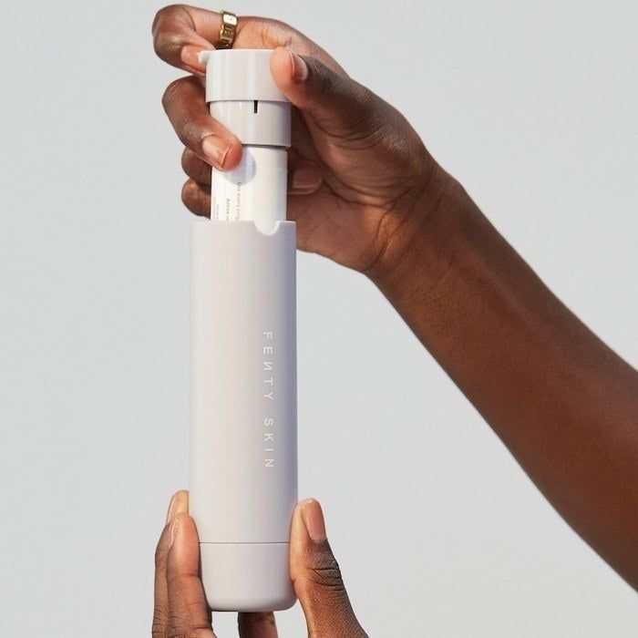 A model holding the Fenty Skin SPF 30 moisturizer tube in their hand.