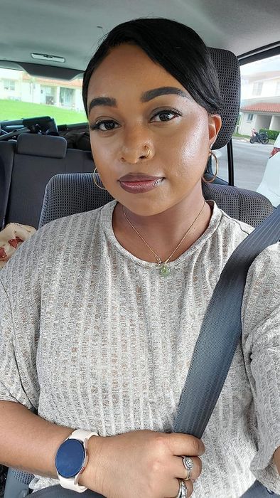 A reviewer wearing the glossy finish on their lips, showing off the shimmering effect.