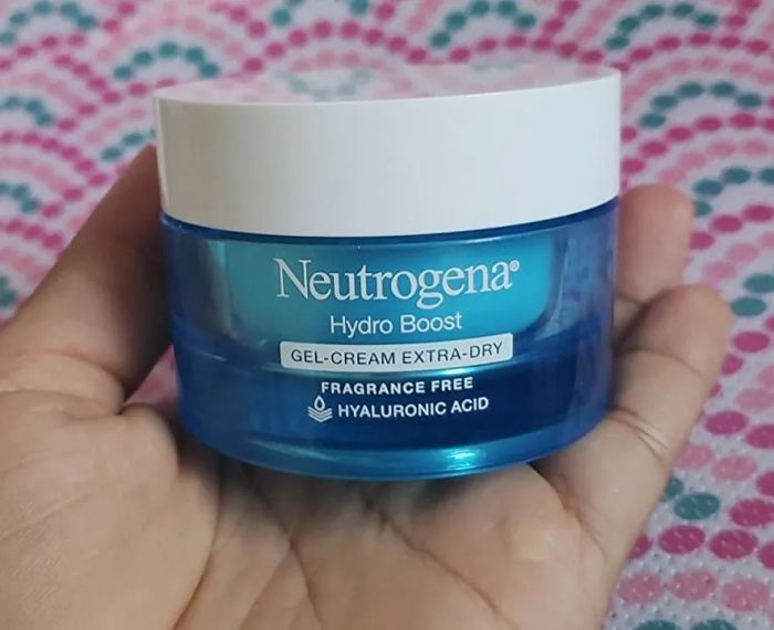 A reviewer holding a blue tub of the moisturizer.