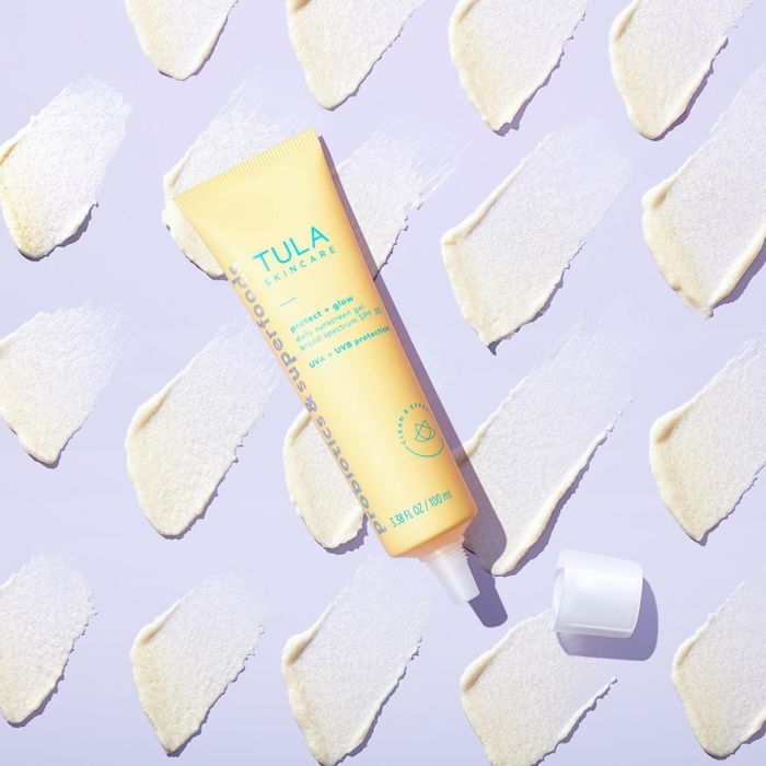 A photo of the TULA sunscreen set against a purple backdrop, with product swatches on display.