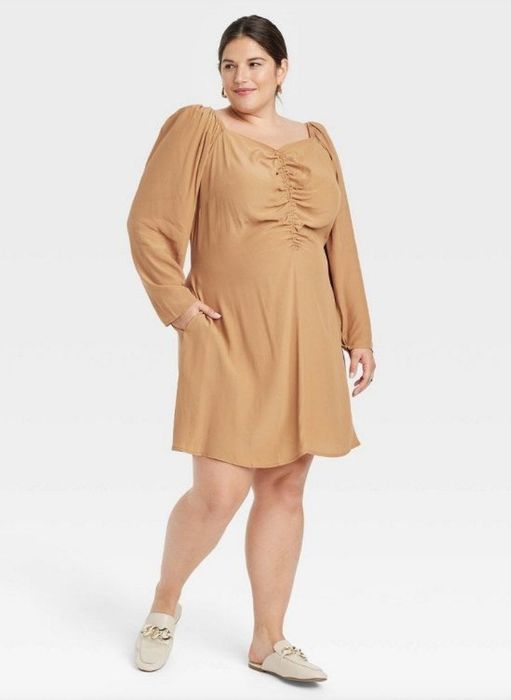 A model dressed in a brown long sleeve ruched dress