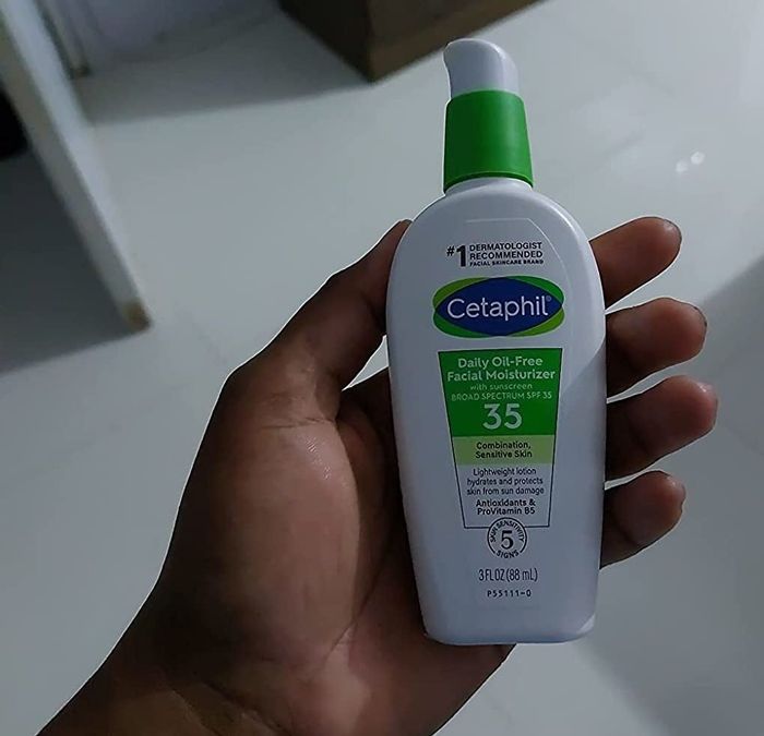 A reviewer holding the Cetaphil moisturizer with SPF, showcasing its benefits.