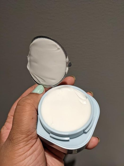 A reviewer showcasing the cream with its lid open.