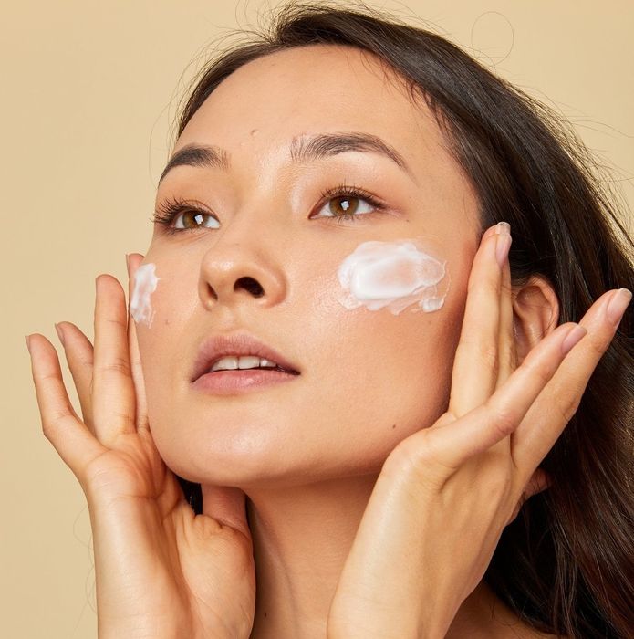 a model applying a foamy facial cleanser to their face