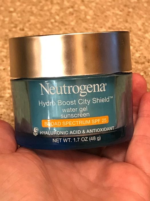 A reviewer holding a jar of the Neutrogena Hydro Boost Moisturizer with SPF, ready to apply.