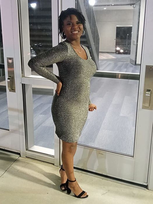 Reviewer wearing a silver glitter long-sleeve dress with black strappy heels