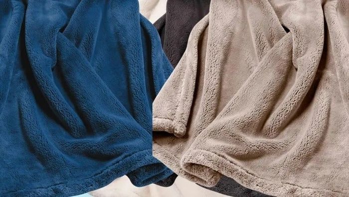 Soft, plush blankets in blue, gray, and beige stacked neatly next to each other