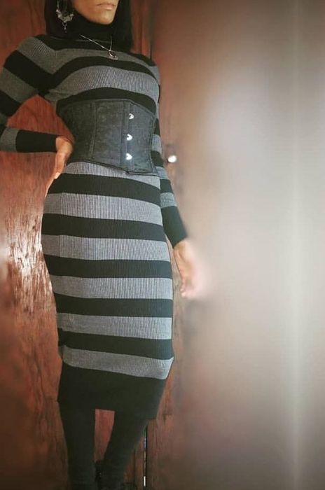 Reviewer showcasing a gray and black pinstripe sweater dress paired with a black corset