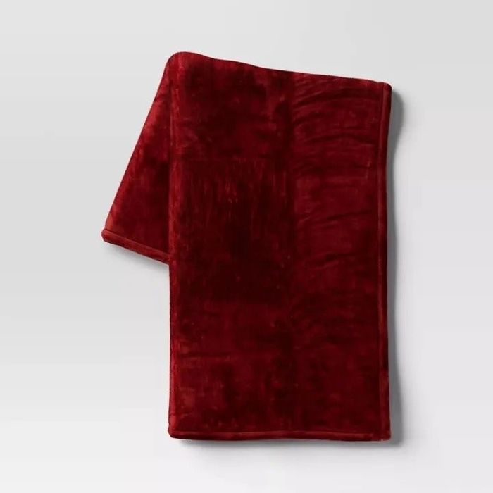 A plush blanket neatly folded against a simple background.