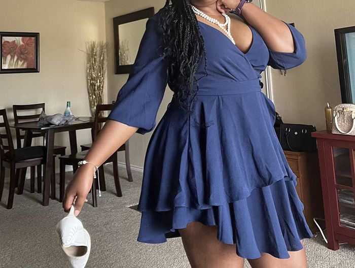 Reviewer modeling a navy blue ruffled tie-waist dress with 3/4 sleeves