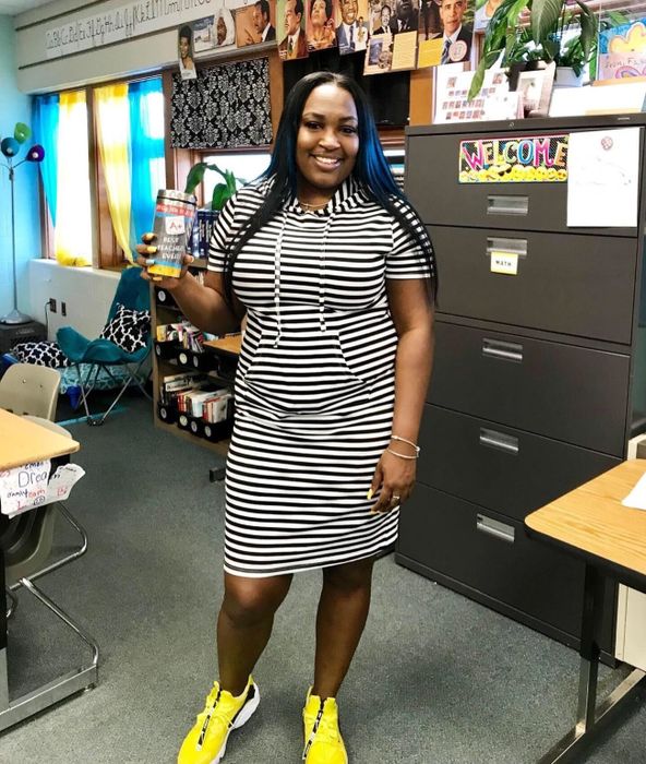Reviewer wearing the dress in black and white stripes paired with yellow sneakers.