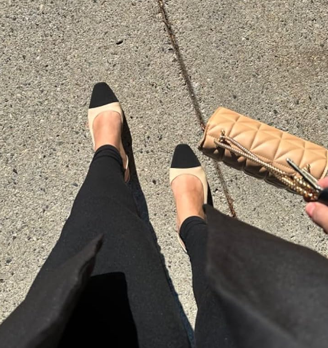 Person wearing black slingback heels with a quilted clutch purse on a sidewalk