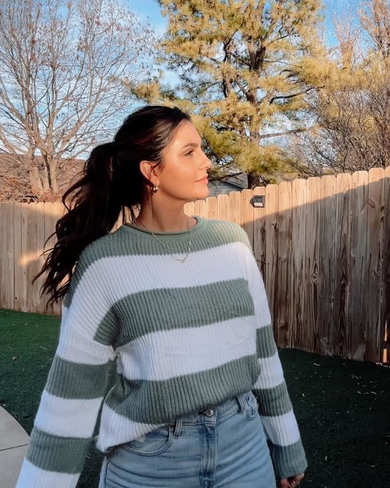 A reviewer modeling the green and white pullover