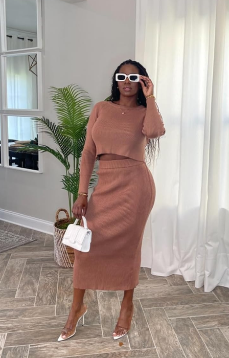 reviewer in a fitted sweater and skirt set, styled with sunglasses, a belt, a white handbag, and clear heels
