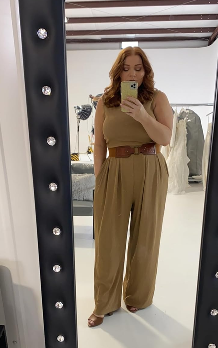 reviewer capturing a mirror selfie in a sleeveless top and high-waisted pants accessorized with a belt