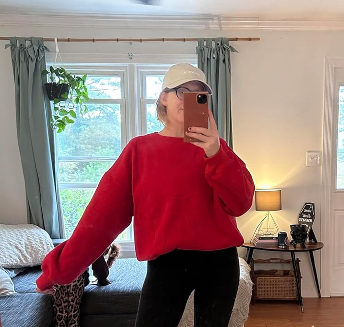 Individual in a snug outfit captures a mirror selfie surrounded by Halloween decor