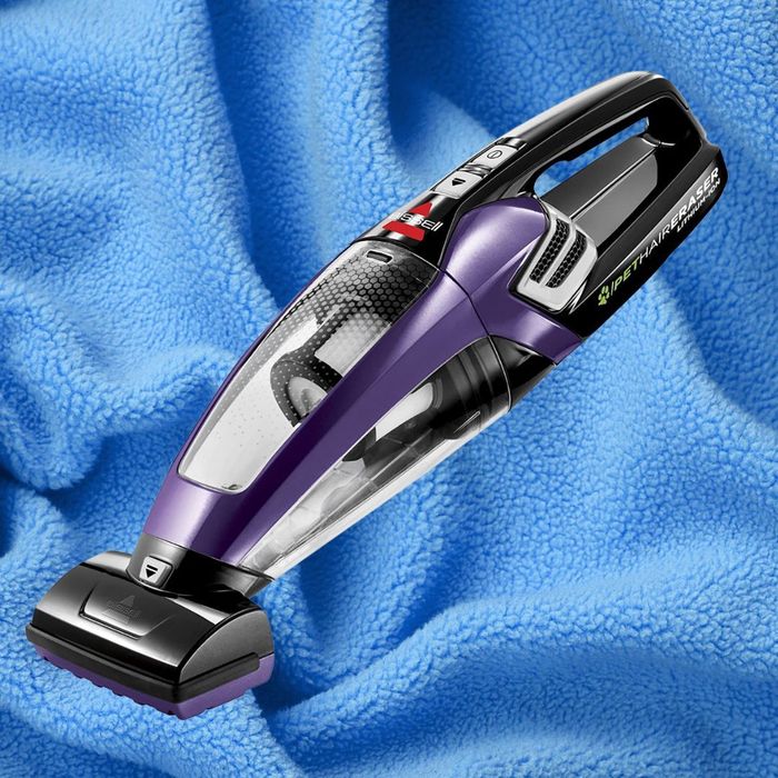 A close-up view of the Bissell Pet Hair Eraser handheld vacuum cleaner, showcasing its design features on a textured surface