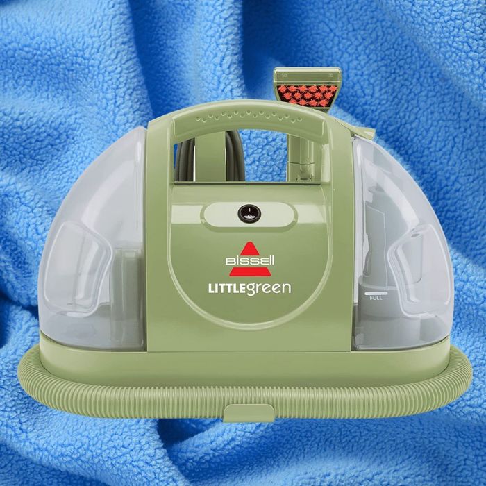 The Bissell Little Green carpet and upholstery cleaner is displayed against a blue, textured background.