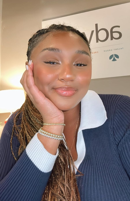 Woman with braided hair and a layered top, taking a selfie to showcase a jewelry-inspired look