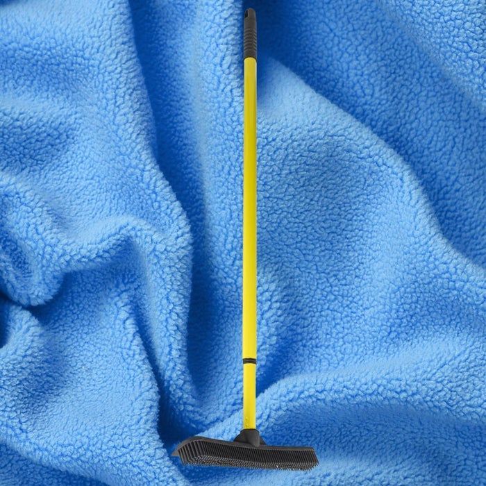 A yellow rubber broom set against a blue fleece background, perfect for removing pet hair and dust from various surfaces