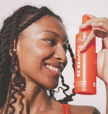 model holding the red facial spray bottle