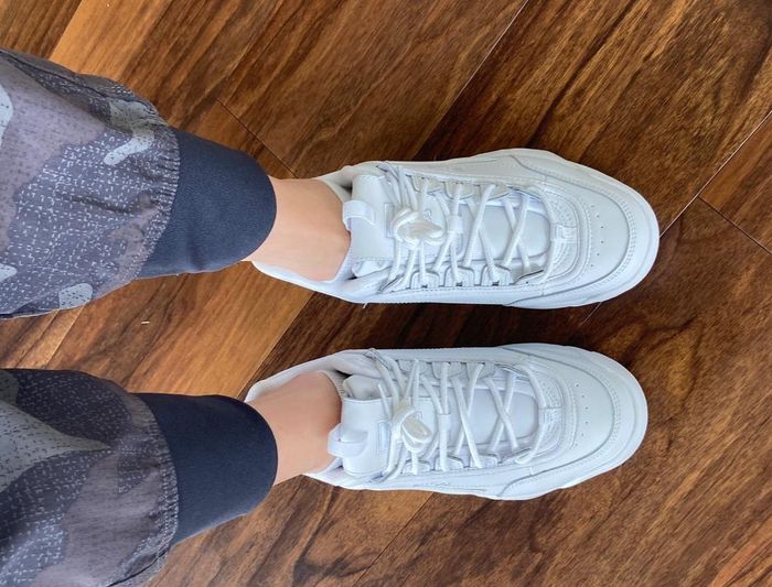 A reviewer modeling the white sneakers