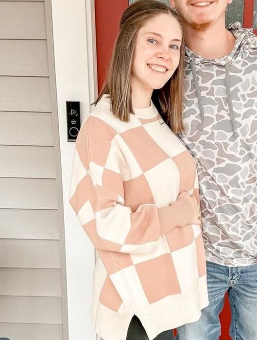 A reviewer showcasing the stylish checkered apricot sweater