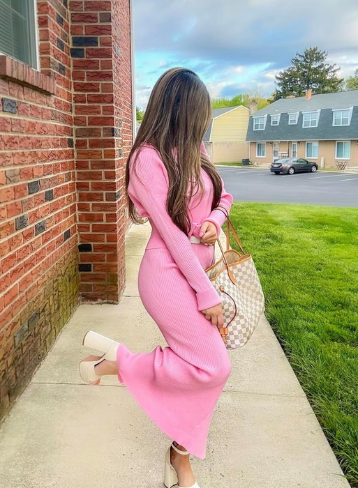 reviewer in a pink ribbed dress paired with a matching cardigan, holding a designer tote bag