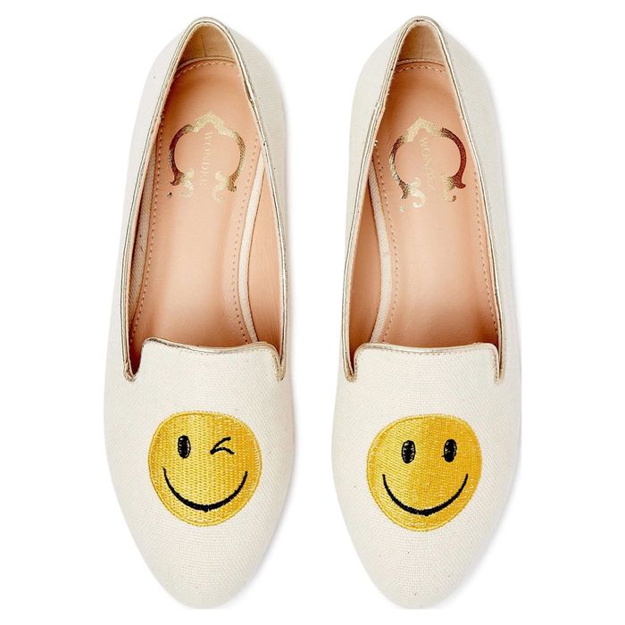 A pair of beige loafers adorned with playful smiley face designs—one winking and the other smiling. Featured in an article highlighting trendy footwear options