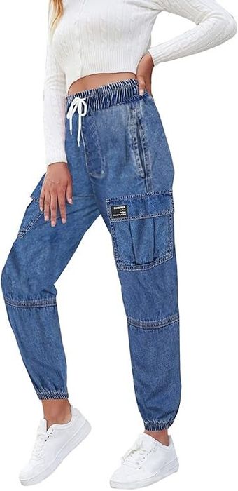 A person models high-waisted blue cargo jeans, complementing them with a white ribbed long-sleeve cropped top and fresh white sneakers.