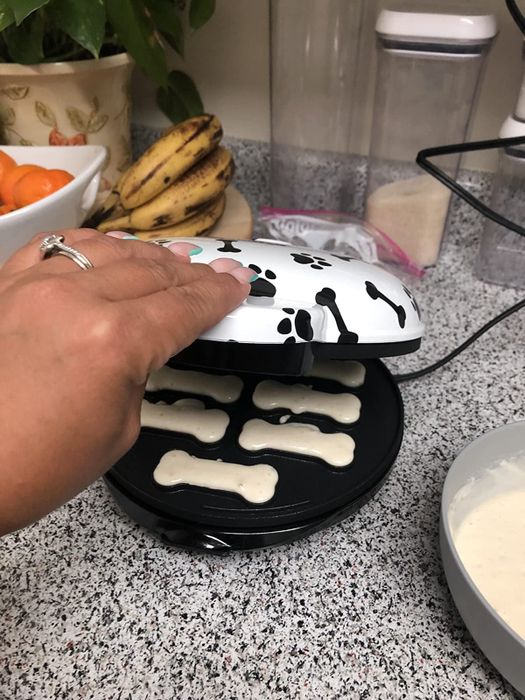 A reviewer’s image of the treat maker, showing the bone-shaped cavities filled with dough, just before closing the gadget.
