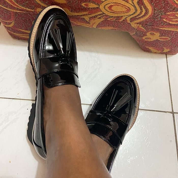A reviewer's photo of someone wearing the sleek black patent loafers adorned with tassels on the toe