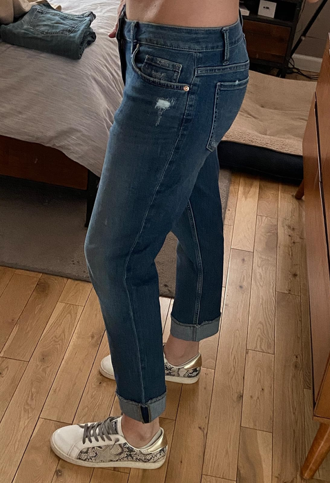 A reviewer highlighting the side view of blue denim jeans.
